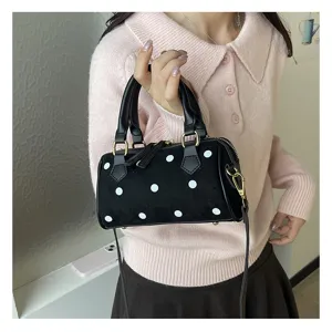 Primer plano detallado del mini bolso Boston negro de lunares blancos con textura de ante suave.