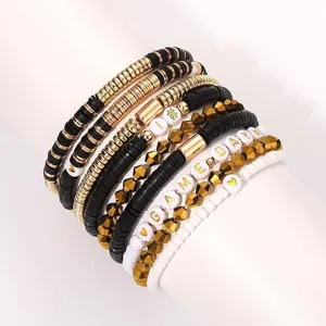 Detailaufnahme von stapelbaren Tonperlen-Armbändern in Schwarz und Weiß mit goldenen Akzenten.