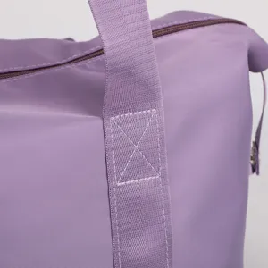Detailed close-up view of the purple travel duffel bag showing durable handle stitching.
