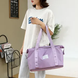 Detail shot of a large purple travel fitness bag held by a model in a clean indoor setting.