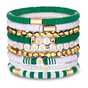 Nahaufnahme Detail von grünen weißen Tonperlen Stapelarmbändern mit goldenen Akzenten.