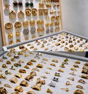 Vista detallada de varios pendientes y anillos dorados de moda expuestos ordenadamente en bandejas.