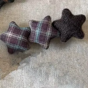 Detailed close-up shot of retro plaid and felt star hair clips, showing fine texture.
