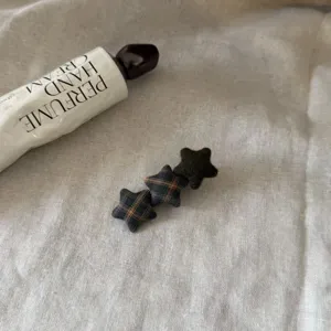 Detailed close-up of Korean retro plaid star hair clip, chic fabric design for cute bangs.