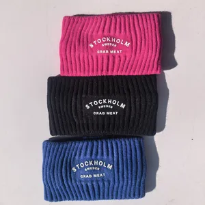 Gros plan de bandeaux d'hiver en tricot épais rose, noir et bleu avec écusson stylé.