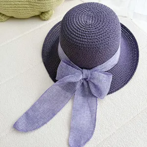 Gros plan du chapeau de paille tressé violet avec élégant ruban de nœud violet clair.