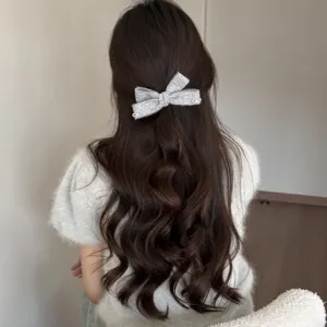 Dettaglio fermaglio per capelli con fiocco scintillante argentato, ideale per acconciature.