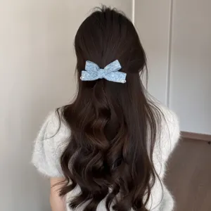 Vista dettagliata dell'elegante fermaglio per capelli con fiocco in tweed blu sui capelli.