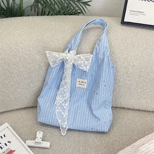 Light blue striped fabric tote bag featuring a delicate white lace bow and charming star patterns.