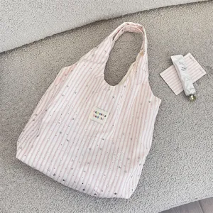 Detailed shot of pink striped canvas tote bag with silver stars and cozy lifestyle props.