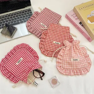 Close-up detail of cute plaid ruffled drawstring storage pouch with delicate mini fabric label.