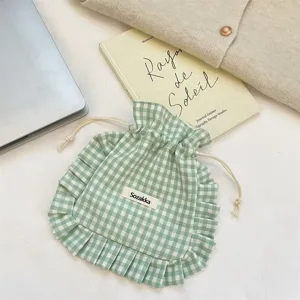 Green gingham drawstring pouch detail with ruffled edge, cute fabric storage bag close-up.