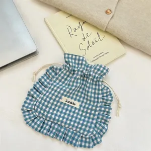 Detailed view of blue and white plaid drawstring pouch with cute ruffle trim design.