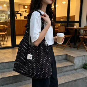 Vista detallada de un bolso tote de lona con lunares en blanco y negro, elegante y práctico.