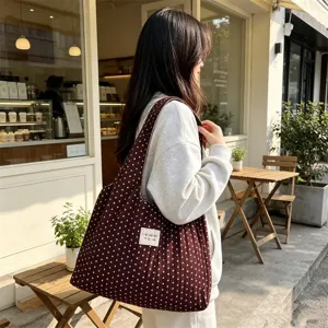Vista detallada del elegante bolso de hombro marrón de lunares con textura arrugada.