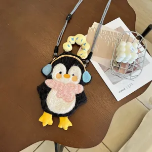 Détail de sac téléphone pingouin en peluche, design dessin animé mignon avec sangle.