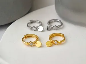 Nahaufnahme Detailansicht von Silber und Gold Creolen mit kleinen runden Anhängern und Kristallen.