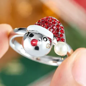 Detalle de un tierno anillo abierto de muñeco de nieve navideño con pedrería roja y perla.