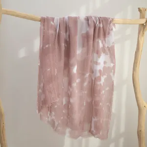 Gedetailleerd uitzicht op een prachtige roze sjaal met batikprint hangend op houten rek.