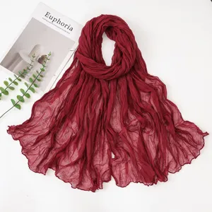 Close-up detail of the deep red crinkled voile scarf showing fine texture and elegant drape.