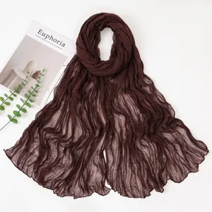 Dark brown crinkled voile scarf detail, elegant pleated long shawl texture close-up.