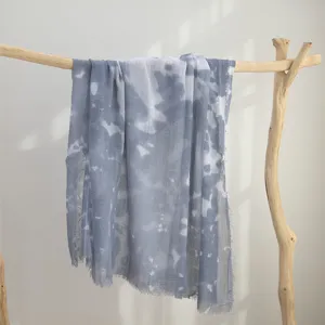 Close-up detail van blauwe aquarel tie-dye katoenen sjaal gedrapeerd op houten tak decoratie.