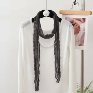 Detailaufnahme eines dunkelgrauen, knittrigen Schals mit weißem Top, elegantes Accessoire.
