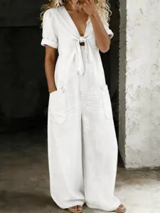 Casual denim jumpsuit detail shot, short sleeves, V-neck tie front, wide leg silhouette.