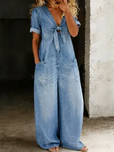 Detailed view of a light blue denim short-sleeve wide-leg jumpsuit with front tie knot and pockets.