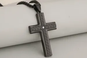 Stainless steel black cross pendant necklace detail featuring textured finish and center crystal.