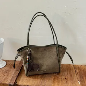 Détail du sac cabas en daim vert foncé avec charm éléphant mignon dans un style rétro.