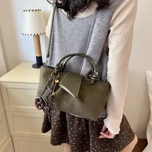 Vue détaillée du sac rétro en daim vert foncé avec poignées nouées élégantes et jolies breloques.
