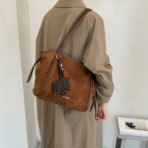 Vue détaillée d'un sac cabas en daim marron avec charm éléphant pour le travail quotidien.