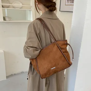 Vue détaillée du sac porté épaule marron en daim vintage sur le modèle, belle texture.