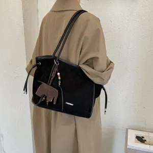 Détail de sac cabas en suédine noire, sac porté épaule vintage minimaliste avec charm éléphant.