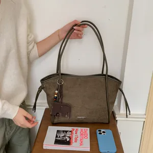 Gros plan sur le sac cabas en suédine vert foncé avec pendentif éléphant et bretelles élégantes.