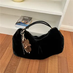 Detalle bolso hombro felpa negro, textura suave esponjosa, colgante osito tierno.