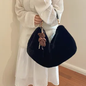 Primer plano detallado de un bolso de hombro de felpa negra suave con un bonito colgante.