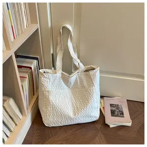 Detailansicht der cremeweißen strukturierten Canvas-Tasche im gemütlichen Lifestyle-Ambiente.