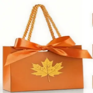 Orange paper gift bag detail shot, featuring elegant ribbon bow and autumn maple leaf design.