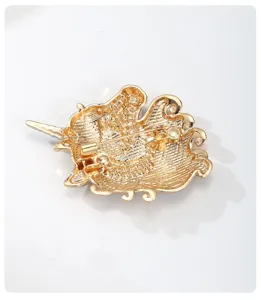 Gold metal alloy brooch back view detail showing secure metal pin clasp and texture.