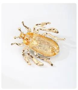 Close-up detail view of the gold-tone metal beetle brooch back structure and secure pin fastening.