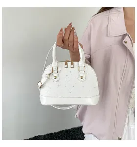Detail de sac a main d'epaule blanc avec motifs d'etoiles, quincaillerie dores et poignee rigide.