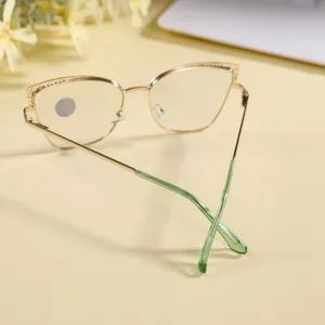 Detail shot of stylish metal cat-eye glasses frame with green temples on clean desk.