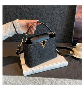 Schwarze glitzernde Umhängetasche mit goldenem V-Metallverschluss für stilvolle Herbstlooks.