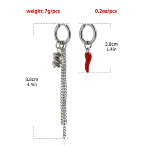 Gros plan de boucles d'oreilles asymétriques en métal avec chaînes et pendentif piment.