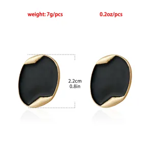 Vista dettagliata di eleganti orecchini ovali neri e oro con un bordo strutturato unico.