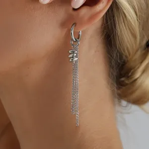 Gros plan détaillé de boucles d'oreilles longues et argentées avec des chaînes suspendues.