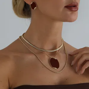 Elegante set di collane ovali rosso vino chic con catena a serpente e orecchini coordinati.