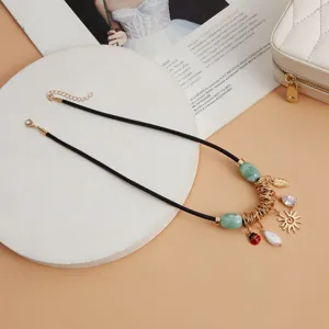 Nahaufnahme Detail der Vintage-Halskette mit grünen Perlen, Charms und schwarzer Kordel.